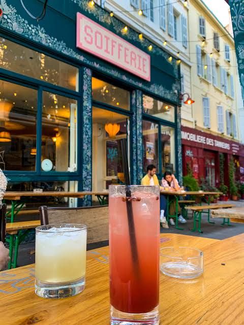 Deux cocktails sur une table de terrasse, devant la façade verte de La Soifferie