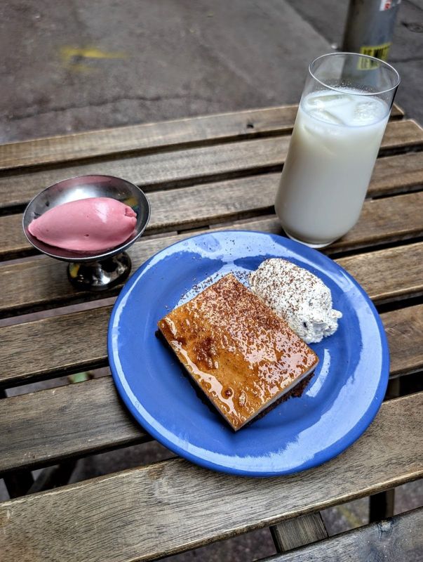 Un dessert et un verre de boisson lactée sur une table en bois en terrasse