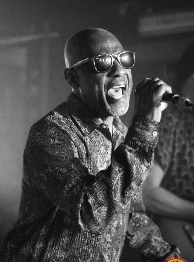 Rudy Mills chante au micro sur la scène du Molotov, en noir et blanc