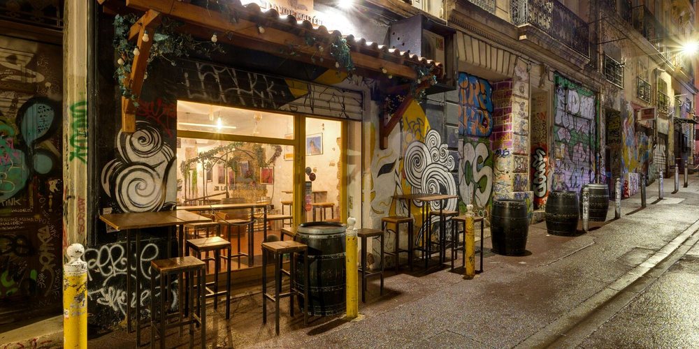 La devanture de La Voie maltée, rue Crudère, la nuit, entre deux murs graffés